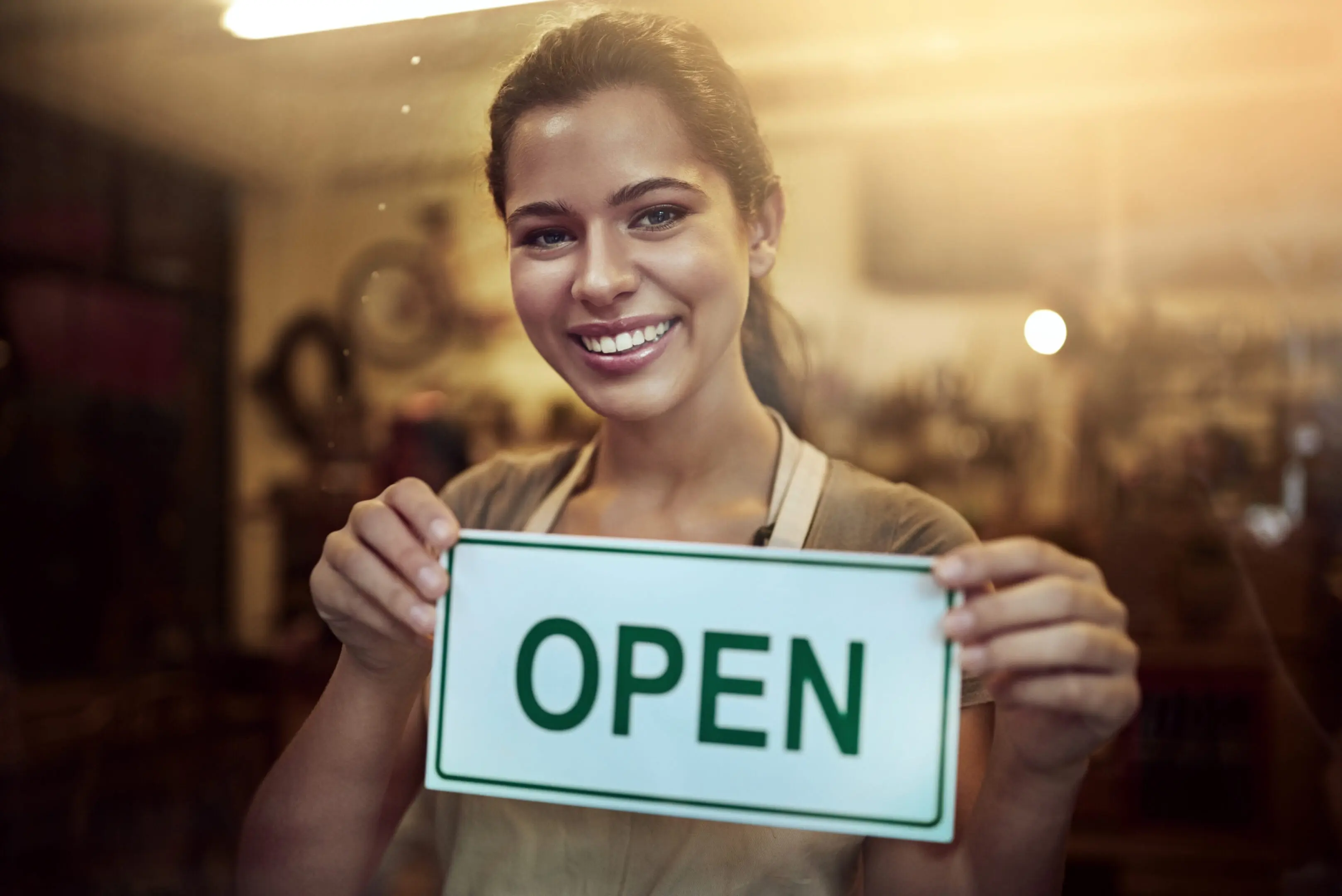 Day 1 of a brand new coffee venture Portrait of a young woman holding up an open sign in her store